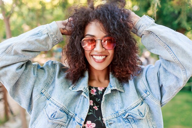 Close up emotional portrait of joyful pretty lady playing with her amazing curly hairs.