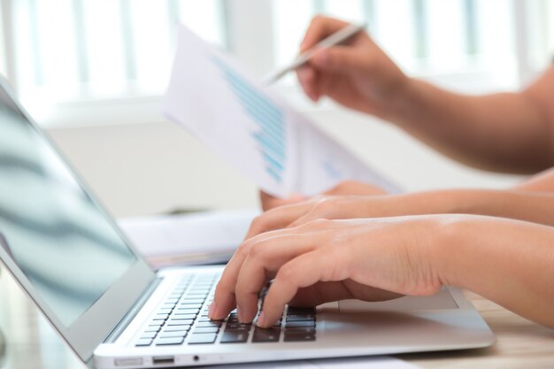 Close-up of employee working with laptop in office