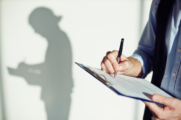 Close-up of employee writing on a clipboard