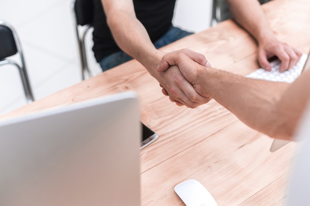 Close up. employees shaking hands in the workplace. people and technology