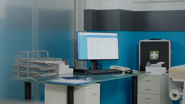 Close up of empty desk for nurses with computer monitor and document files at medical clinic. Nobody in doctors office with healthcare instruments and professional equipment for checkup