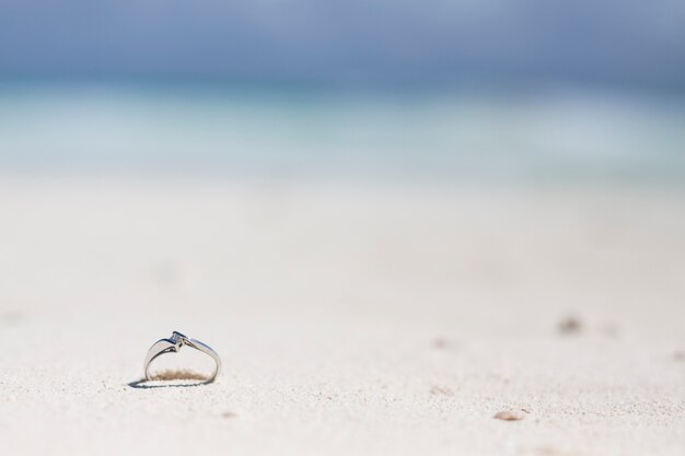 Close-up engagement ring in the sand