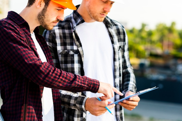 Free photo close-up of engineer and architect  looking at clipboard