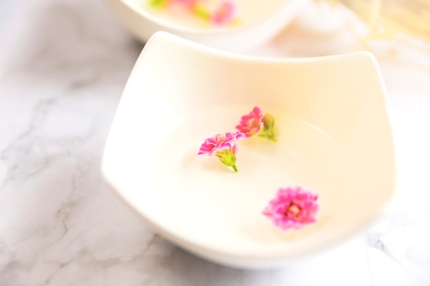 Close-up of essential oil with pink flower petals in bowl