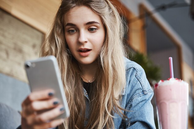 屋外でスマートフォンの画面を見ている興奮した女の子のクローズアップ