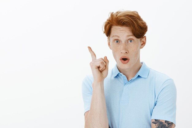 Close-up of excited redhead man raising finger in eureka gesture, have great idea