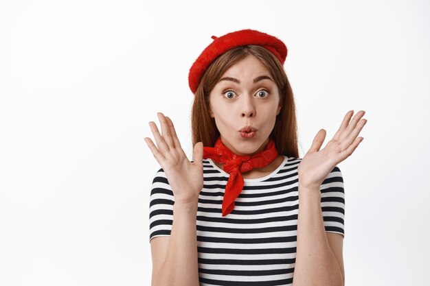 Close up of excited and surprised girl looks amazed with awesome super good news, jumping from excitement and joy, clap hands, standing over white wall