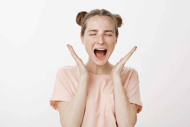 Close-up of excited teenage girl posing against the white wall