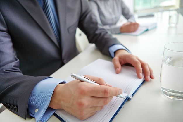 Close-up of executive writing in his notebook