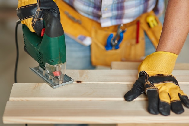 Close up on experienced carpenter drilling in a wooden plank