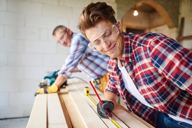 close up on experienced carpenter and his younger employee