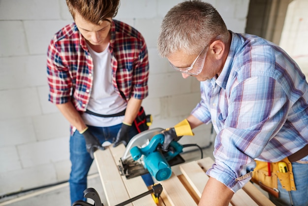 Free photo close up on experienced carpenter and his younger employee