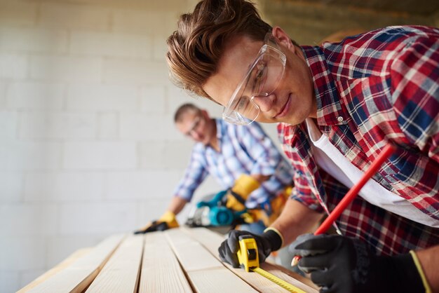 close up on experienced carpenter and his younger employee