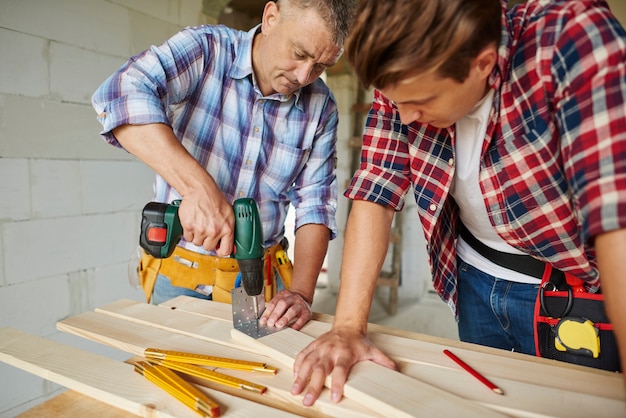 Close up on experienced carpenter and his younger employee