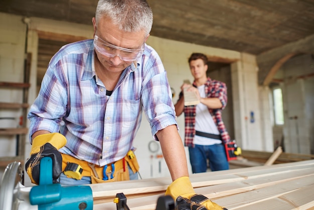 close up on experienced carpenter and his younger employee