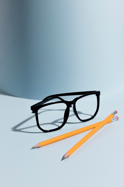 机の上のクローズアップの眼鏡と鉛筆