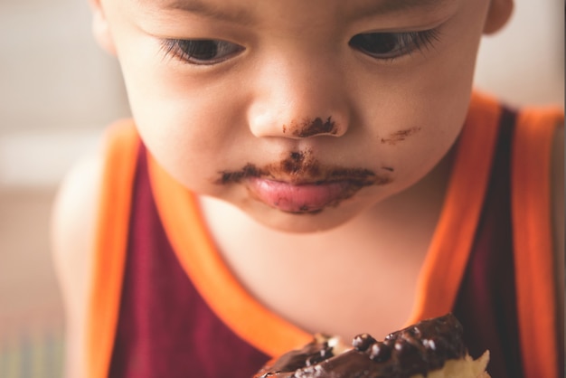 Close up face of hungry little boy eaitng hot donut