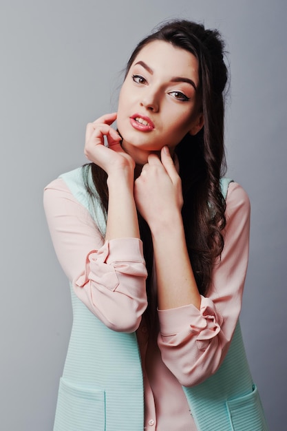 Close up face portrait of young brunette girl wearing in pink blouse turquoise jacket ripped jeans Fashion studio shot