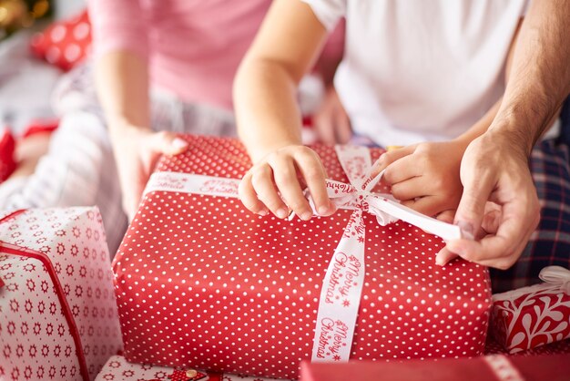 Закройте руки семьи во время открытия рождественских подарков