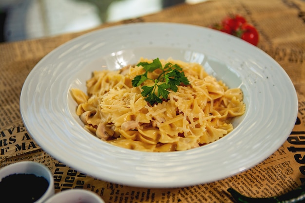 Close up of farfalle with mushroom and chicken garnished with parmesa and parsley