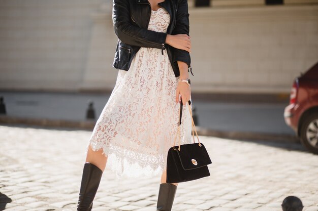 Close up fashion details of attractive woman walking in street in fashionable outfit holding purse, wearing black leather jacket, spring autumn style