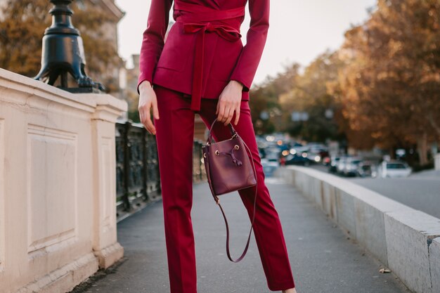 Close up fashion details of stylish woman in purple suit walking in city street, spring summer autumn season fashion trend holding purse