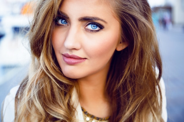 Close up fashion portrait of seductive sexy woman with big blue eyes ,full lips , prefect skin and long fluffy curled hairstyle. Natural make up.