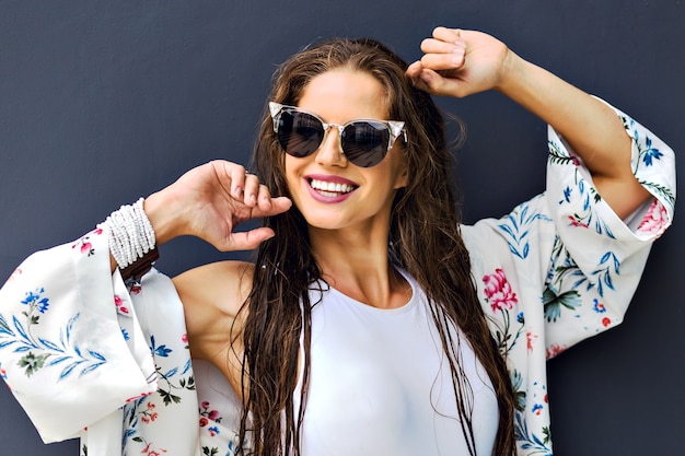 Close up fashion summer portrait of stunning brunette woman posing at gray background, long wet hairs after swimming