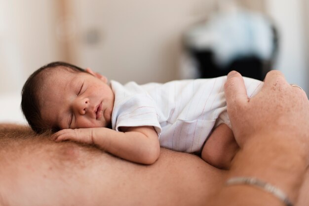 Close-up father holding sleepy baby on his chest