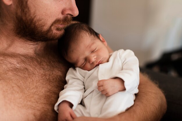 Close-up father hugging sleeping baby