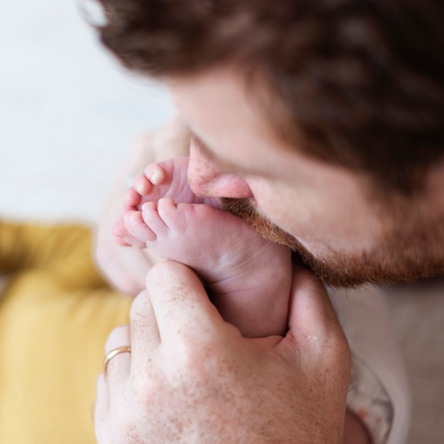 Free photo close-up father kissing baby's feet