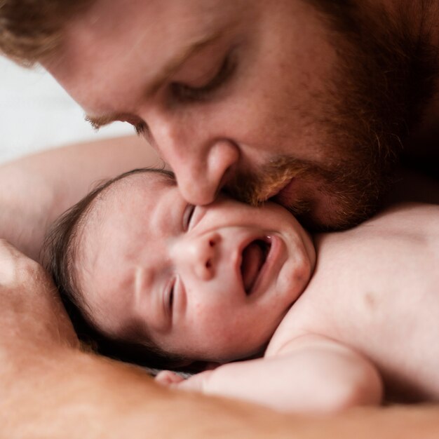 Макро отец целует угрюмого ребенка