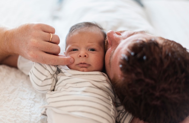 Close-up father laying in bed near baby