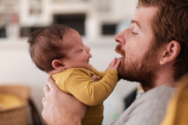 Close-up father playing with baby indoors