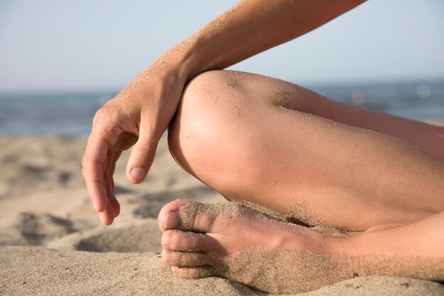 Close-up of feet covered in sand at the beach