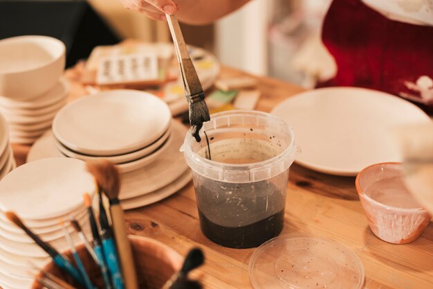 Close-up of female artisan painting the ceramic plate with paintbrush