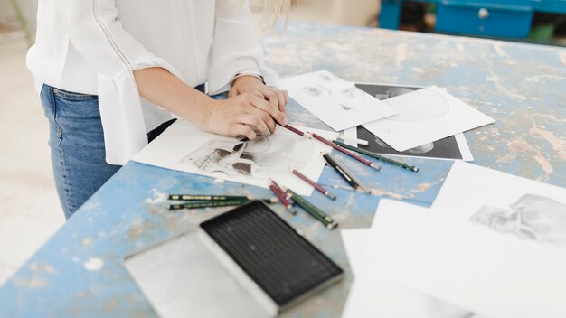 Close-up of female artist drawing with pencil on workbench