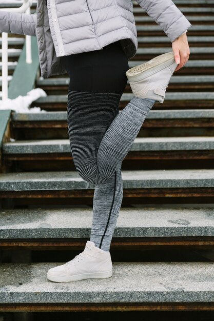 Close-up of female athlete stretching her leg on staircase