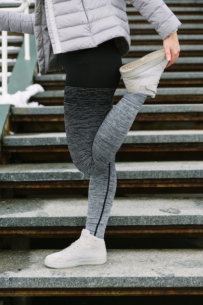 Close-up of female athlete stretching her leg on staircase