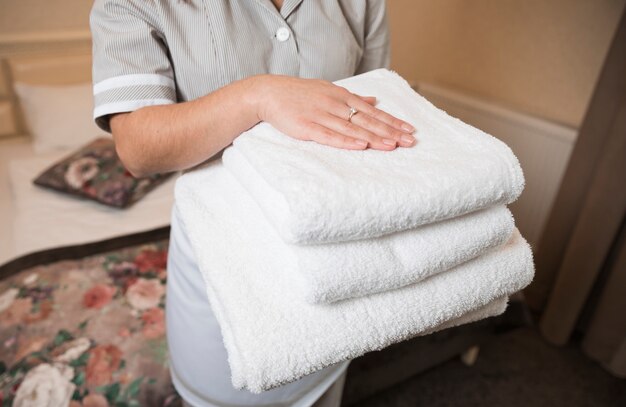 Close-up of female chambermaid holding clean soft folded towel in hand