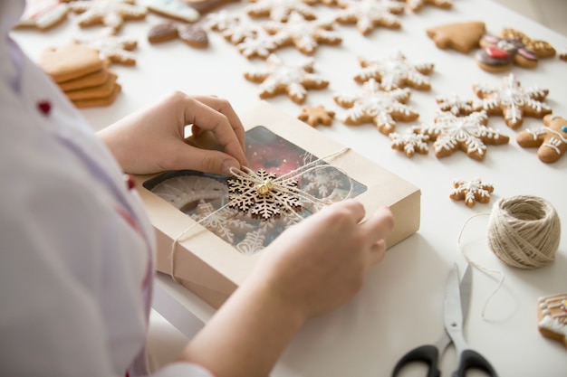 Close up of female confectioner hands wrapping a box