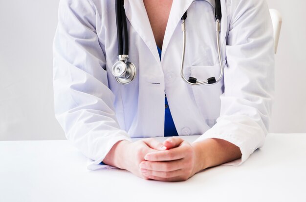 Close-up of female doctor with stethoscope around her neck with hands on desk