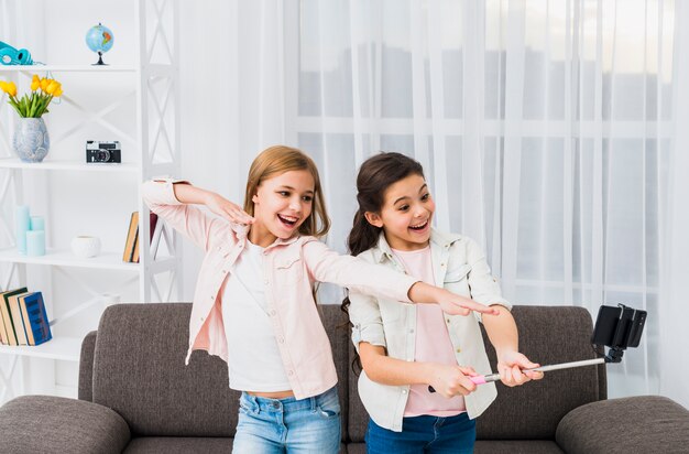 Close-up of female friends taking self portrait on smart phone in the living room