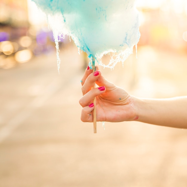 Close-up of a female hand holding blue candy floss