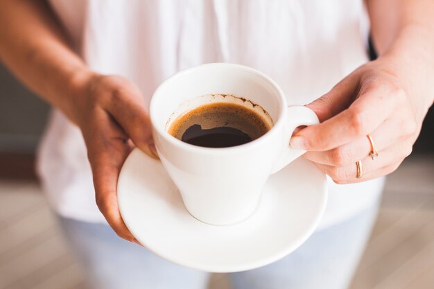 Крупным планом женская рука держит вкусную чашку кофе
