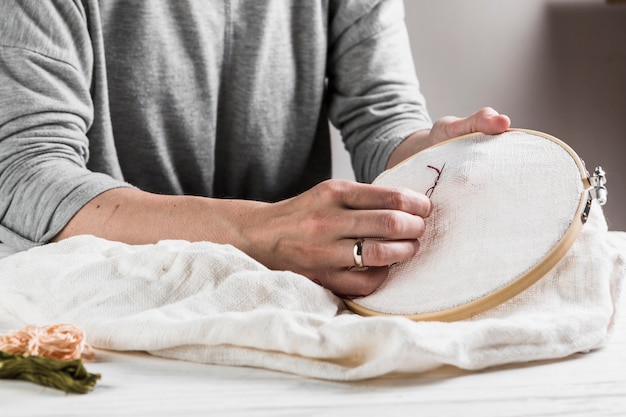 Foto gratuita primo piano del ricamo cucito a mano femminile su tessuto bianco