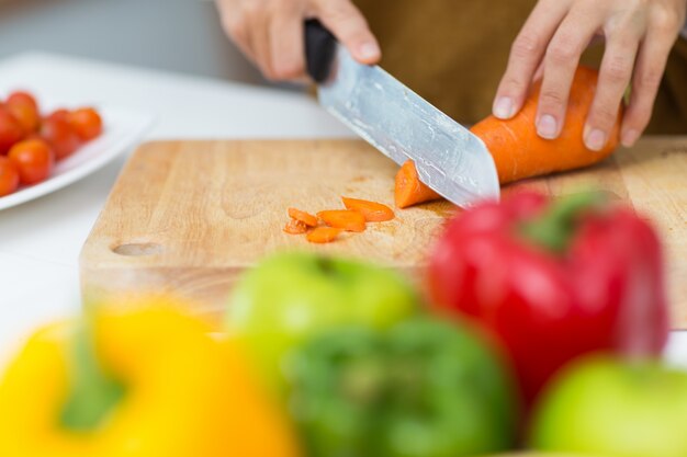 Close-up of female hands cutting carrot on board