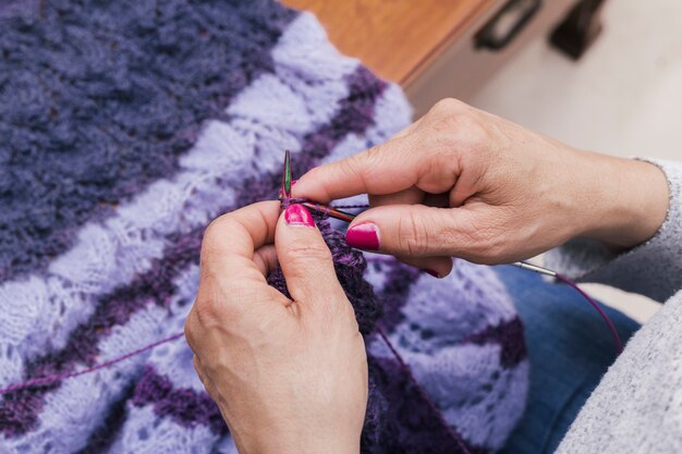 Крупный план женских рук, вязание пурпурной шерсти