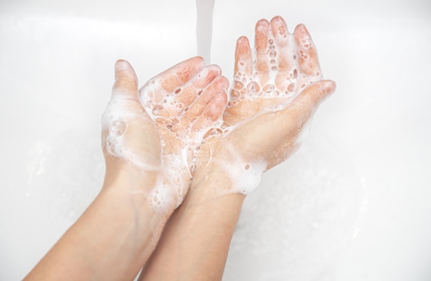 Free photo close up of female hands in soapy foam on a light background.