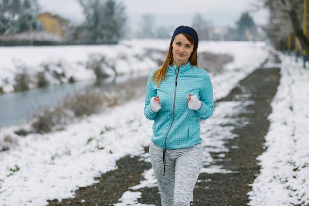 Close-up of female jogger jogging on snowy landscape